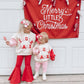 Two children in matching christmas outfits with a 'Merry Little Christmas' banner in the background